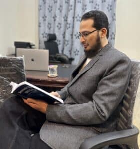 Behzad Hussain reading a book, Semantic SEO and AI written by Sergey Luck, in his office